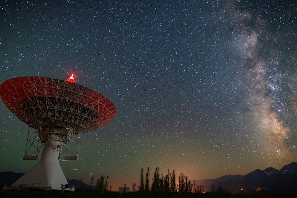 Satellite dish under a starry night sky, representing telecommunications and signal technology